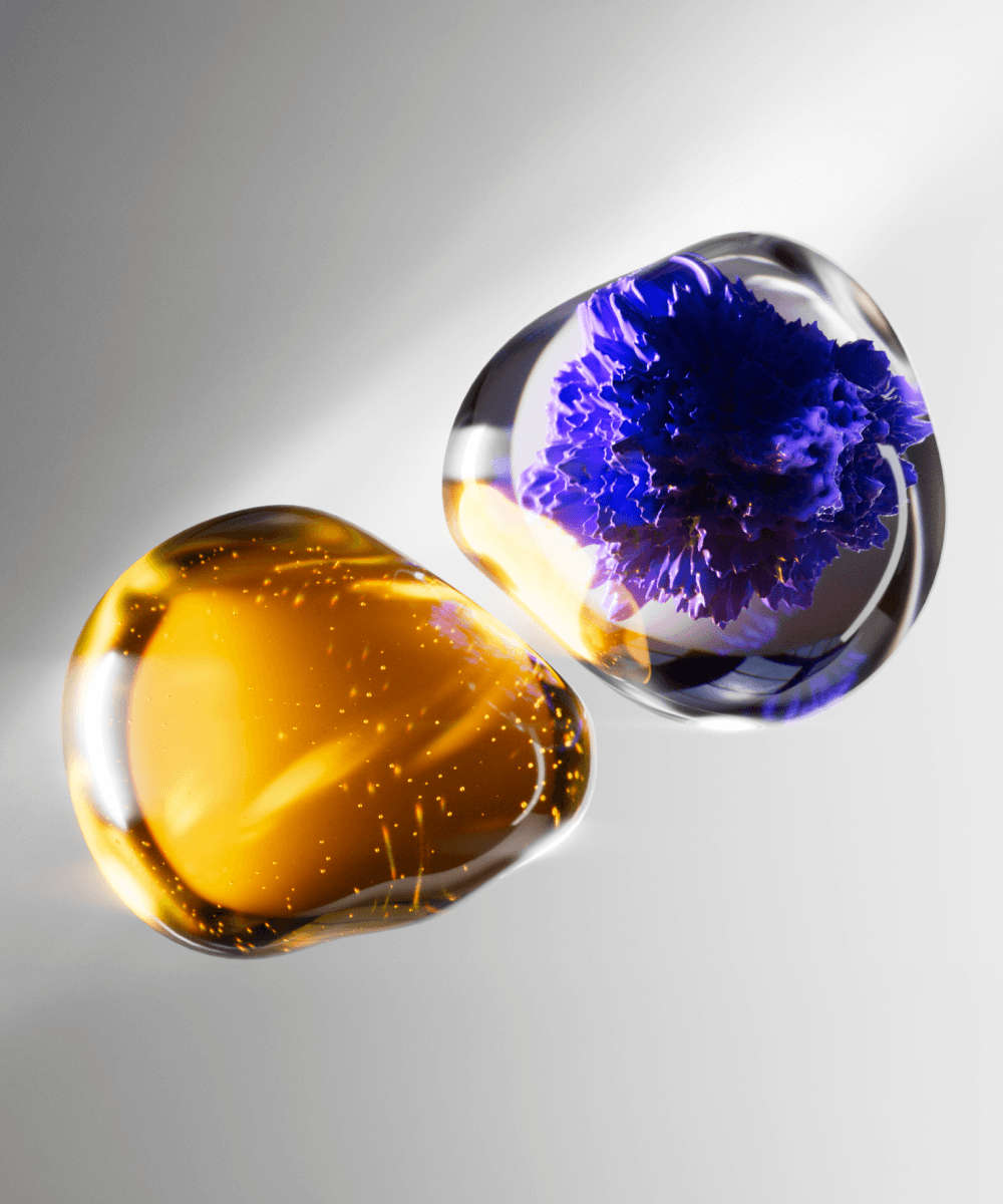 Superchouette- Deux pierres lisses et transparentes semblables à du verre ; l'une contient des tourbillons et des bulles d'or, l'autre renferme une structure cristalline vibrante de couleur pourpre. Elles reposent toutes deux sur une surface grise légèrement éclairée.