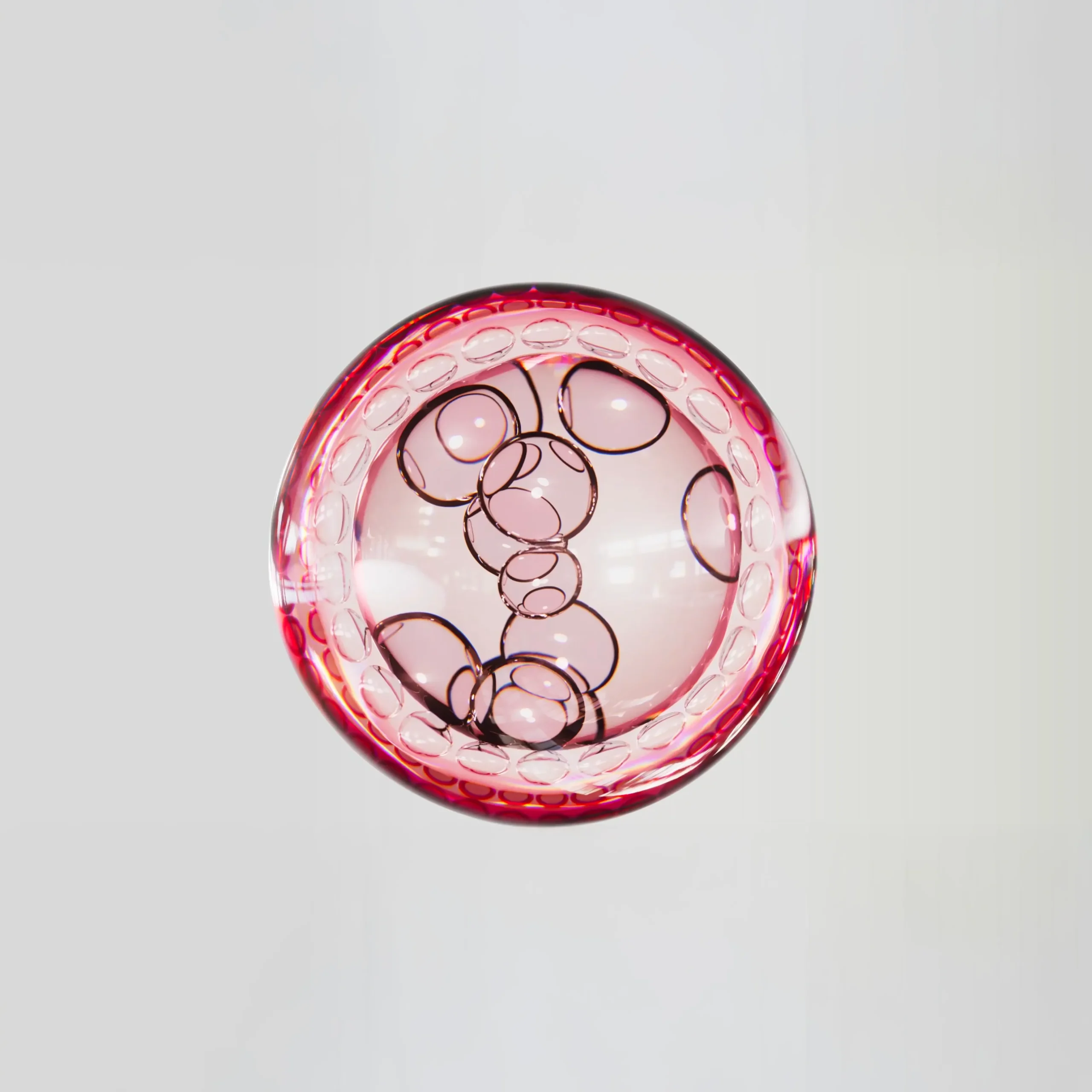 Superchouette- Un objet rond en verre avec un bord rouge rosé et des motifs circulaires noirs à l'intérieur, vu d'en haut, sur un fond blanc uni.