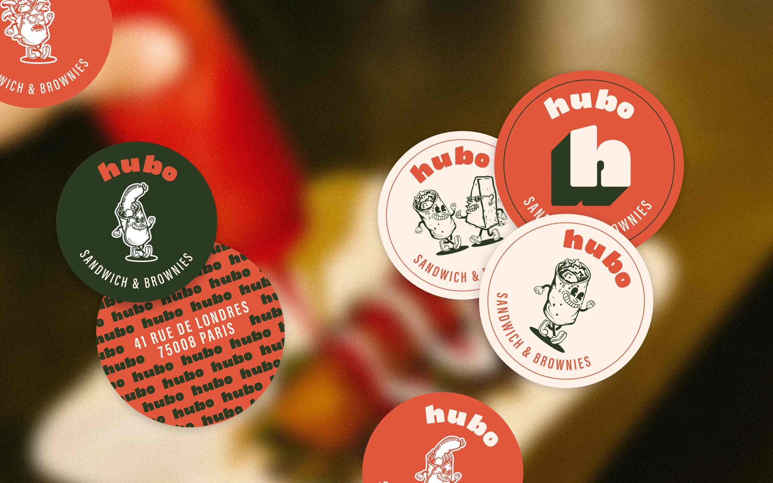 Superchouette- Autocollants ronds assortis portant la marque hubo SANDWICH & BROWNIES, représentant des personnages de sandwichs en dessin animé et de différentes couleurs, dispersés sur un fond flou.
